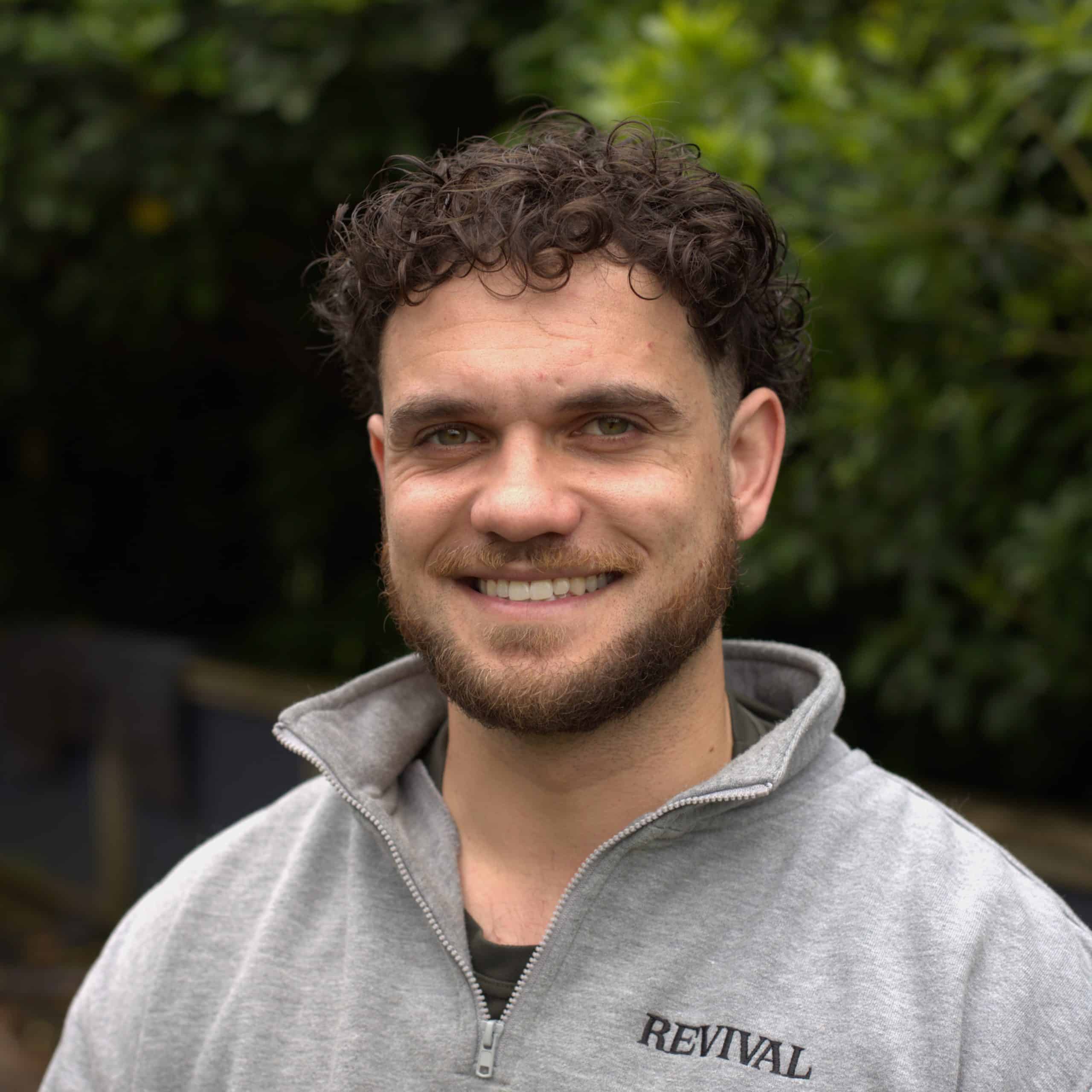 Photo of Micha Milne in a blue shirt and tie - dark curly hair and sunglasses on his head. Micah is a builder at Linear Homes - Auckland building company